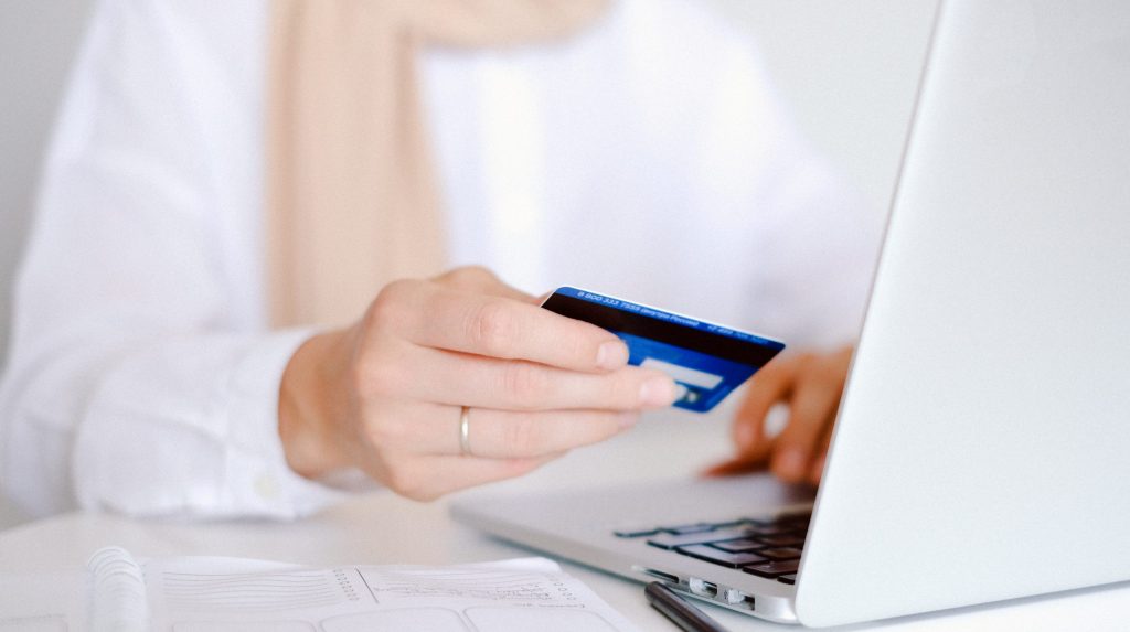 Person in white long sleeve shirt holding credit card