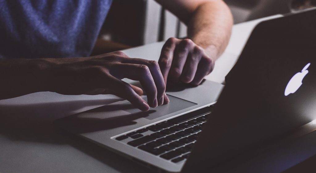 Person touching open macbook on table