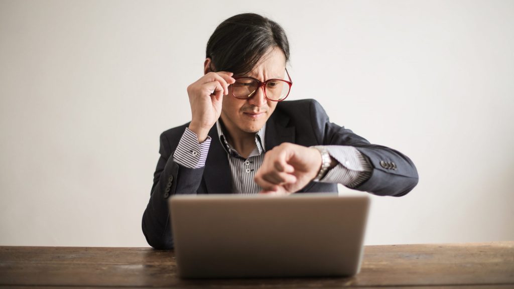 Confused businessman checking time on wristwatch