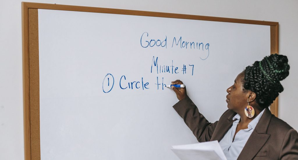 Black female teacher writing on whiteboard