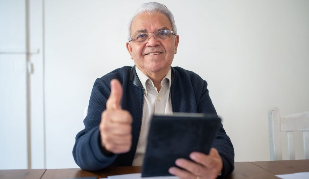Man in black jacket holding black tablet and showing thumb up