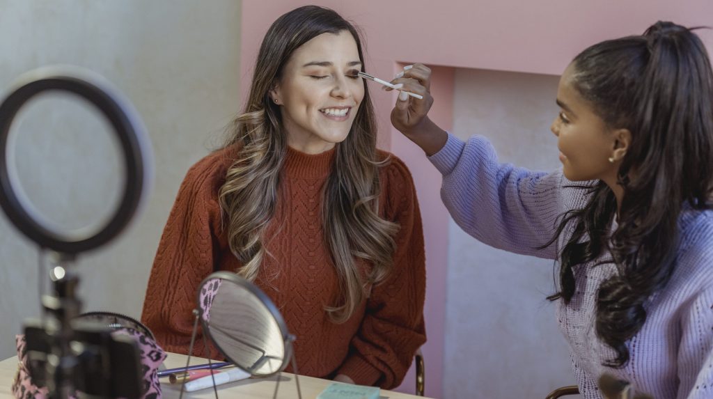 Black beauty blogger applying makeup on model during live broadcast