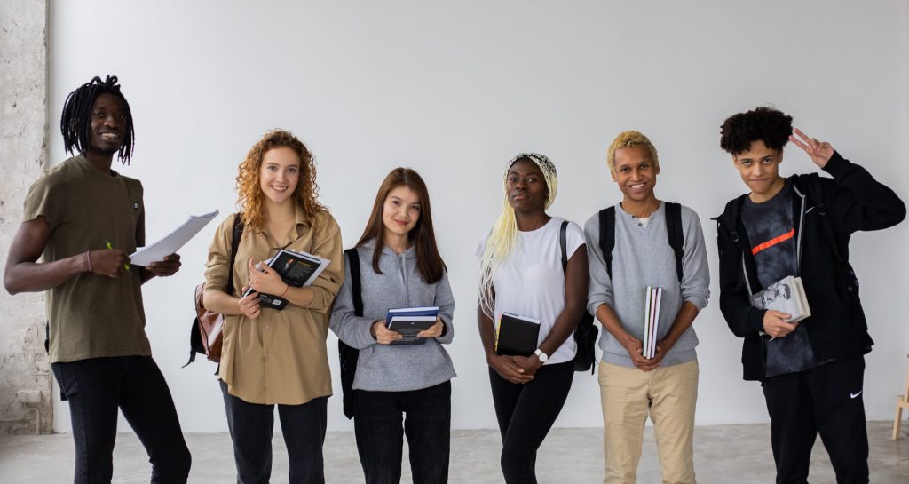 Positive multiethnic team of students standing with books