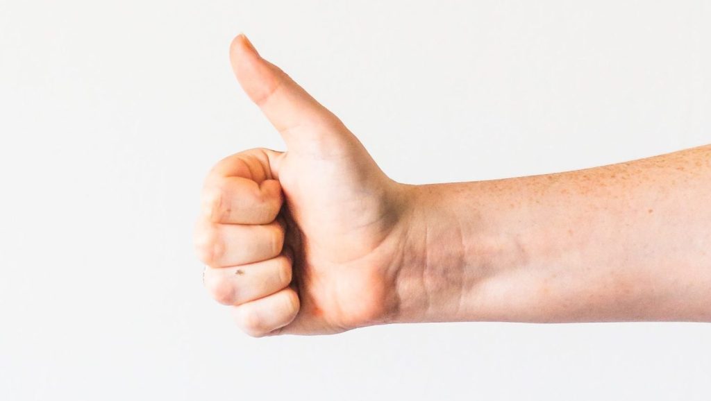persons right hand doing thumbs up