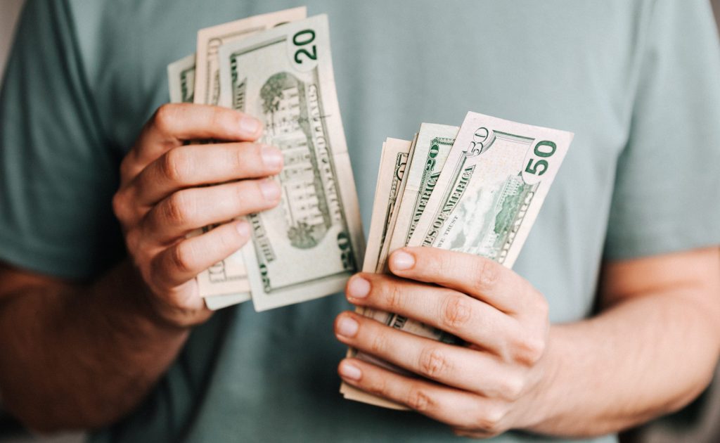 Crop man counting dollar banknotes