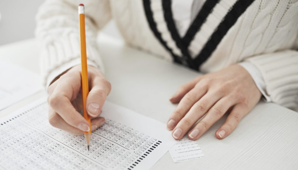 A person writing on paper while cheating