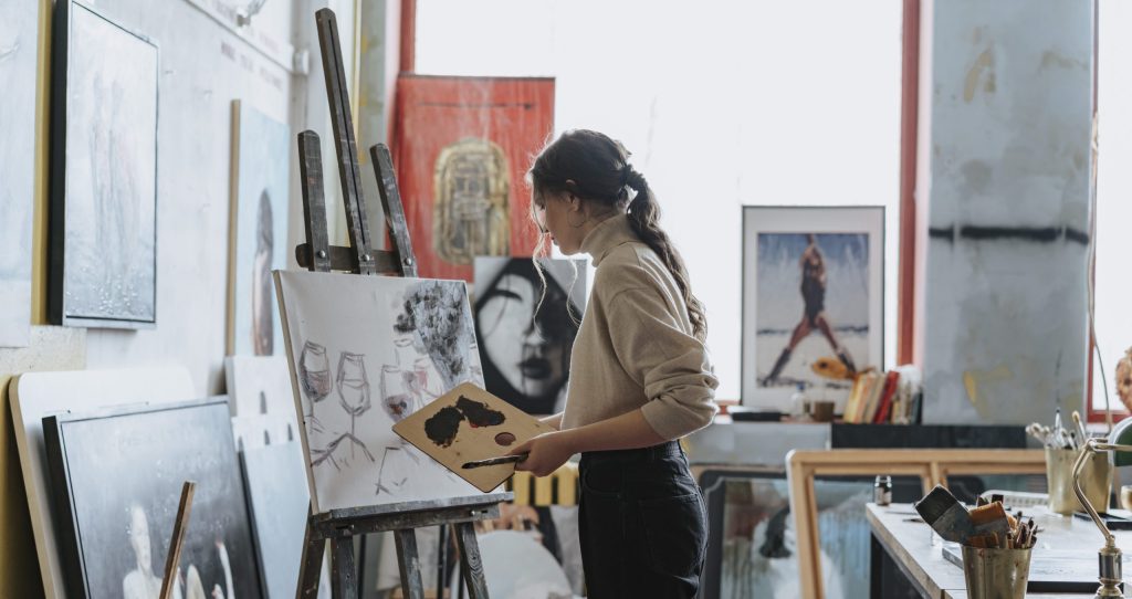 A woman painting wine glasses on a canvas