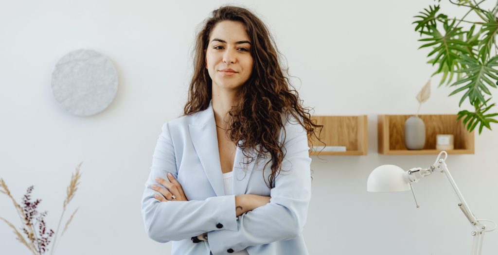 Woman in sky blue blazer standing near white wall