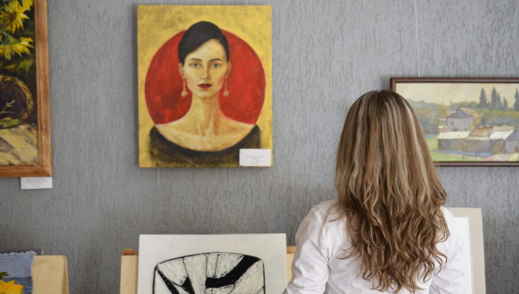 Woman looking at paintings displayed on the wall