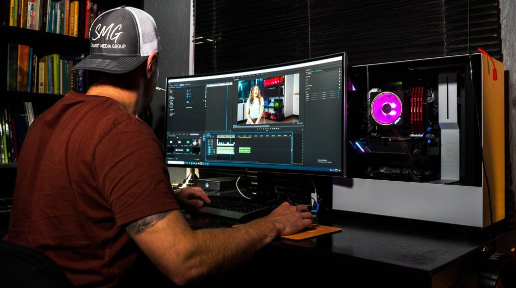 man in red t-shirt sitting in front of computer