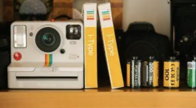 A Polaroid camera and rolls of film on a shelf